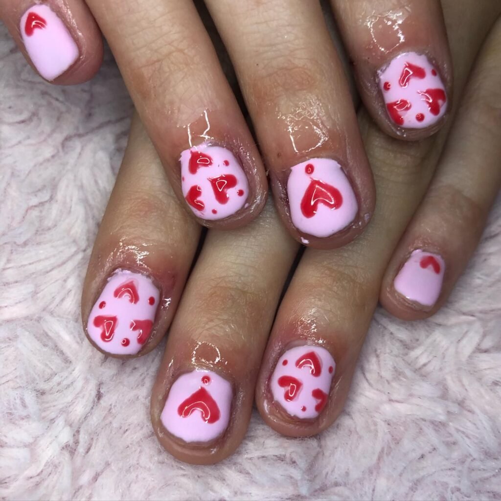 Classic Valentine’s Day nails featuring red and pink heart designs with a glossy finish for a romantic touch