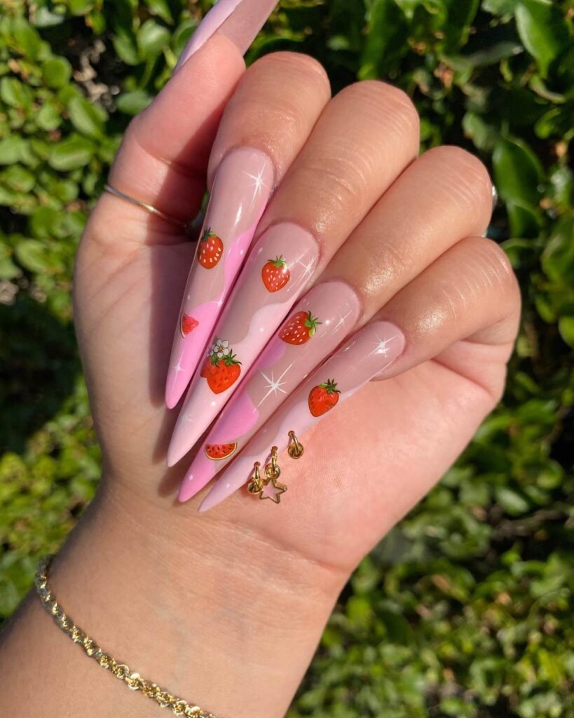 Bright red strawberry nail art with green leaves and white seeds, showcasing a fun and creative summer manicure design on a woman's hand.